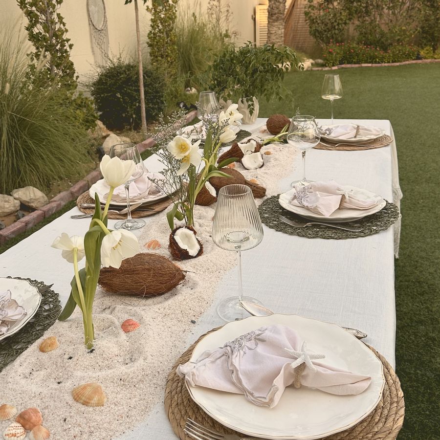 A beach-inspired table in the garden with sand, shells, coconuts and tulips