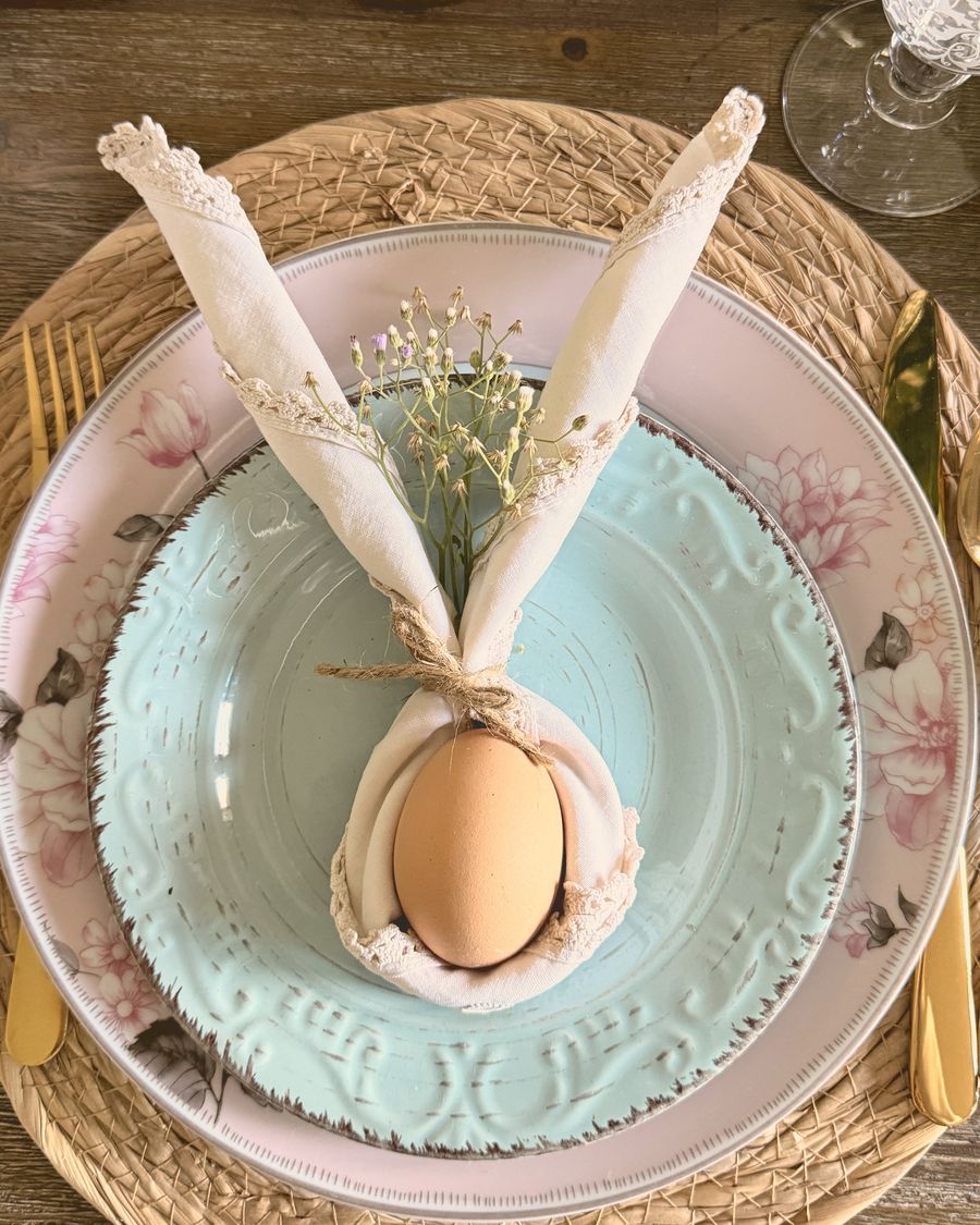 A linen napkin folded into bunny ears around an egg on a mint plate
