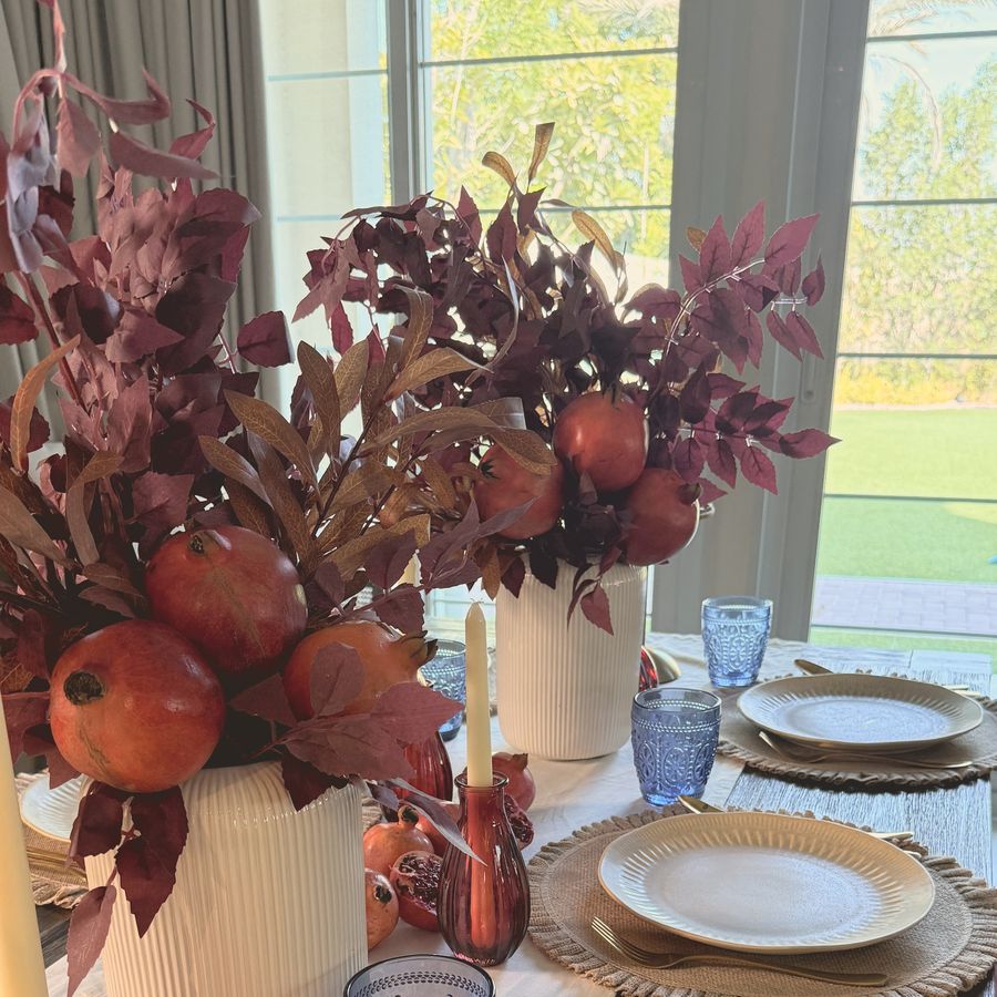 Pomegranates and deep red leaves in white vases with blue glasses
