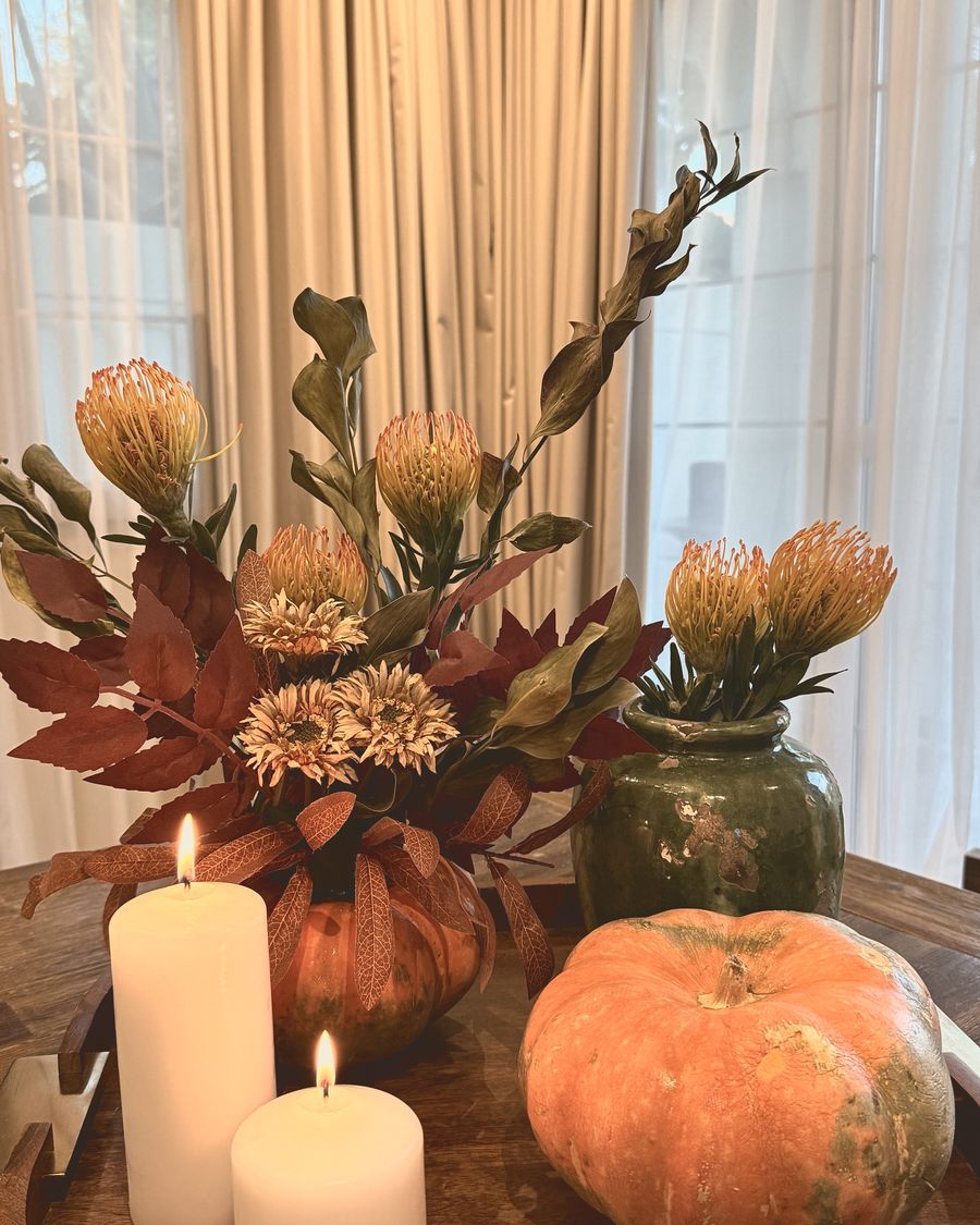 A statement autumn piece with proteas, pumpkins and candles