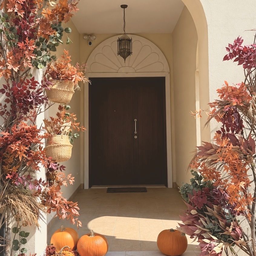 An entrance framed with autumn branches and pumpkins on the steps