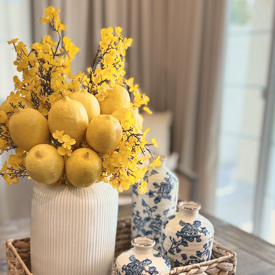 Lemons and yellow blossom in a white vase with blue and white jars